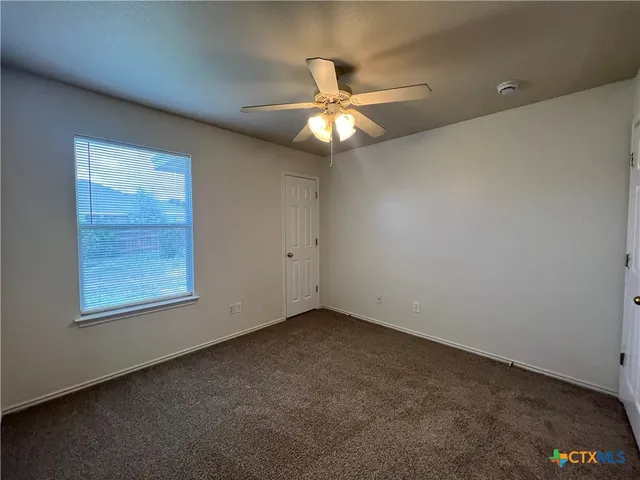 an empty room with a window and a fan