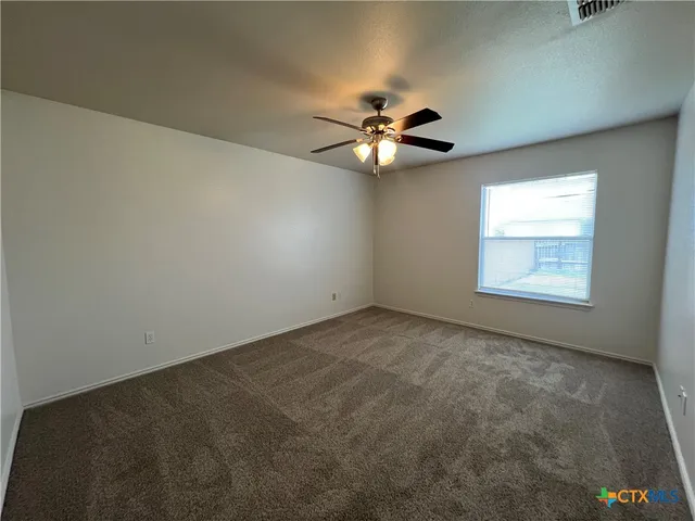 an empty room with a window and a ceiling fan