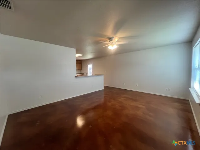 an empty room with a fan and a window