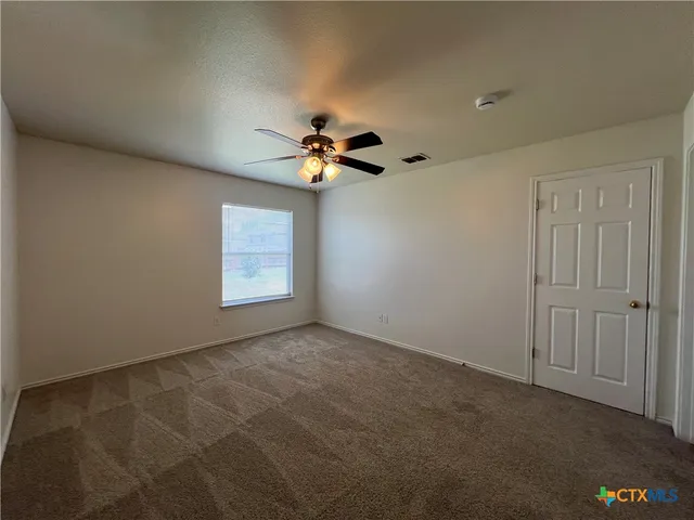 an empty room with windows and fan view
