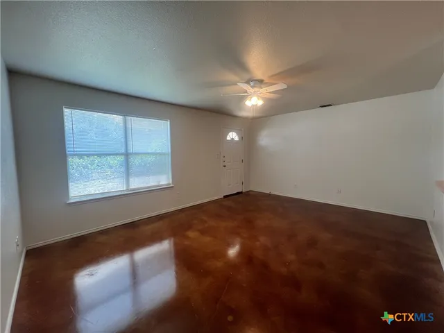 an empty room with windows and fan