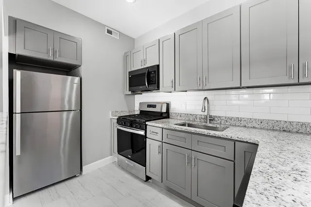 a kitchen with stainless steel appliances granite countertop a refrigerator stove a sink and a microwave