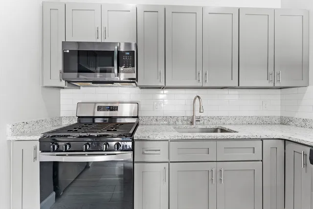 a kitchen with stainless steel appliances granite countertop a sink stove and microwave