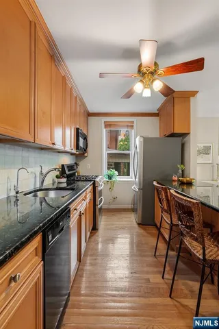 a kitchen with stainless steel appliances granite countertop a sink a stove a refrigerator cabinets and chairs
