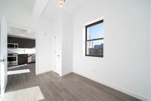 a view of a hallway with wooden floor and a kitchen