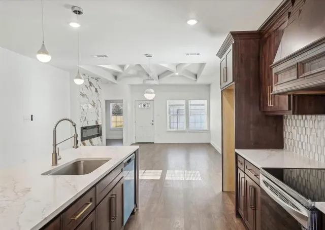a kitchen with stainless steel appliances granite countertop a sink a stove and a wooden floors