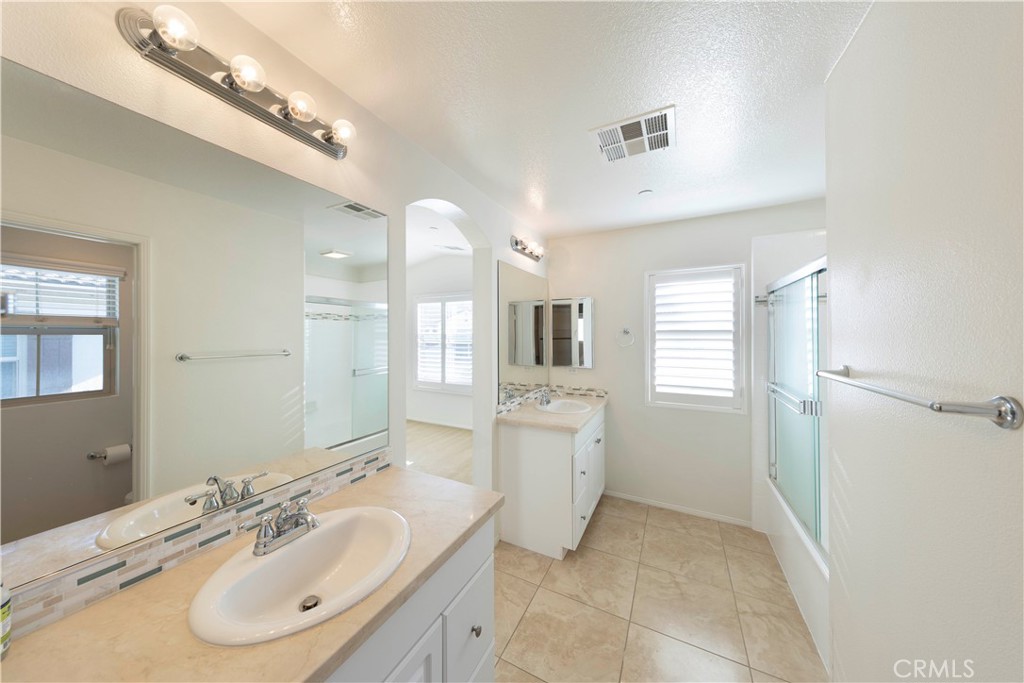 90 Hedge Bloom Irvine, CA 92618 - Photo 16 of 22 a bathroom with a granite countertop double vanity sink a mirror and a shower