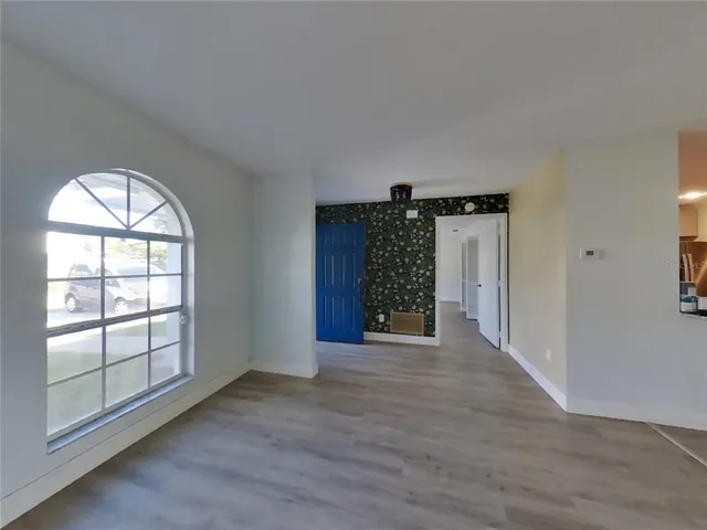 an empty room with wooden floor cabinet and windows
