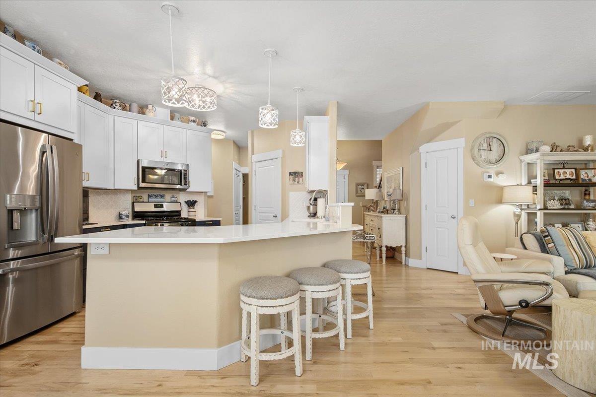 2264 East Comisky Street Meridian, ID 83646 - Photo 11 of 47 Kitchen with backsplash, a kitchen breakfast bar, appliances with stainless steel finishes, and decorative light fixtures