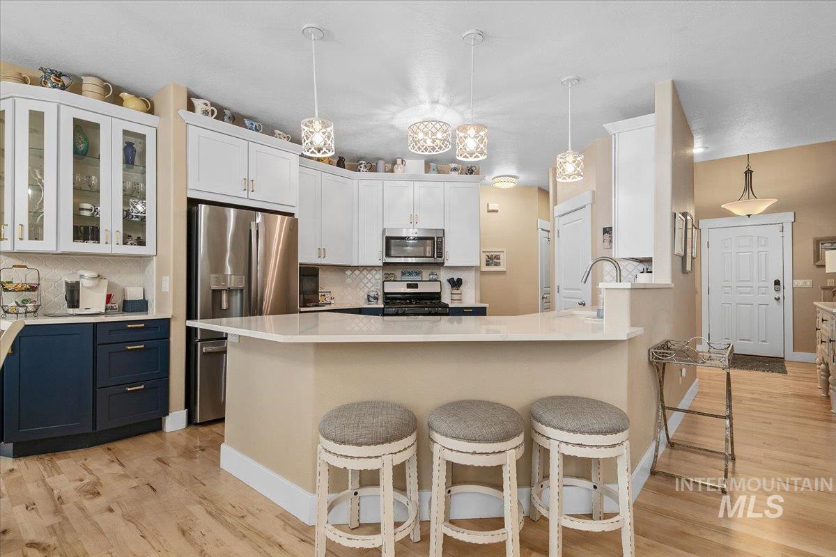 2264 East Comisky Street Meridian, ID 83646 - Photo 12 of 47 Kitchen with decorative light fixtures, backsplash, a kitchen bar, and white cabinetry