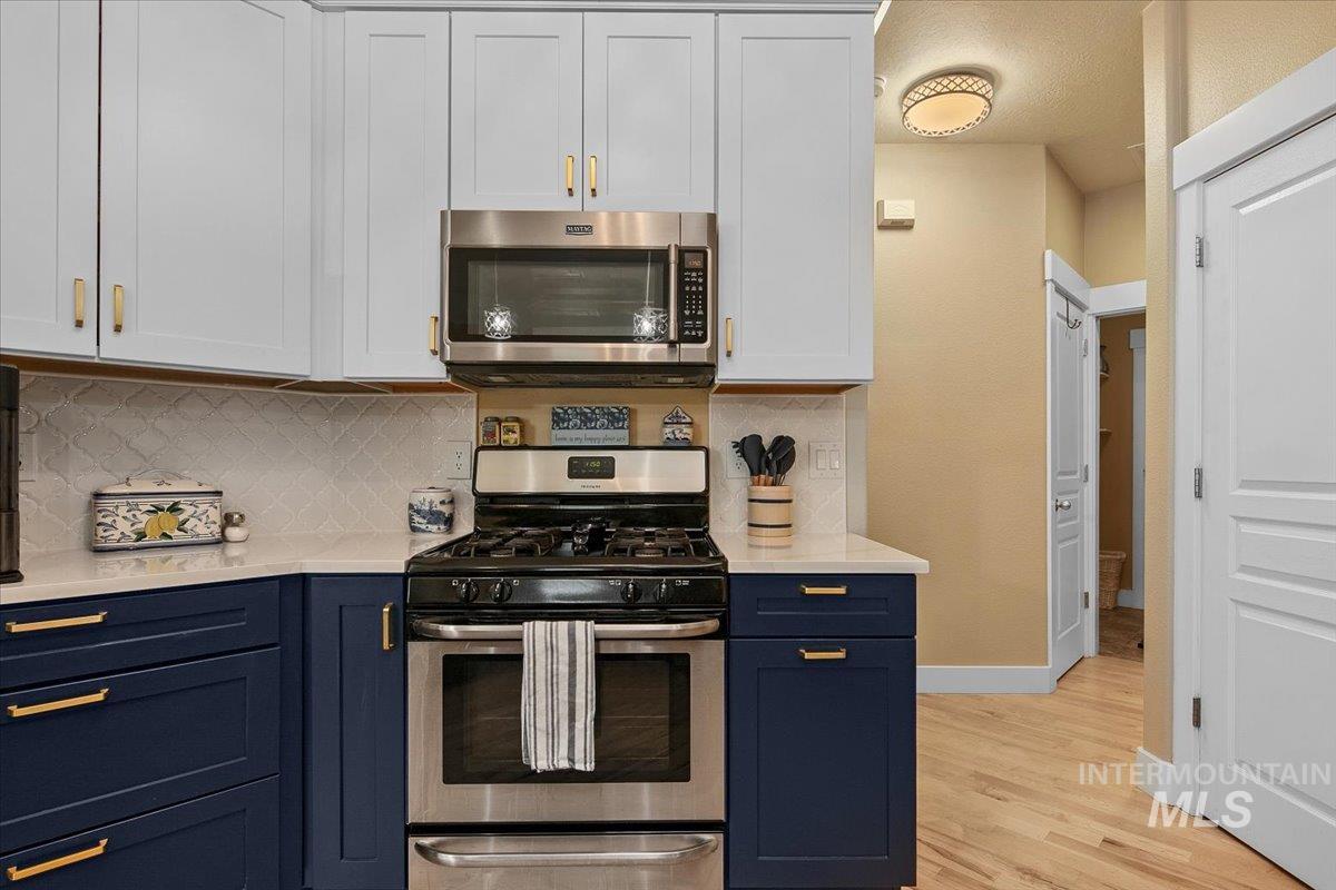 2264 East Comisky Street Meridian, ID 83646 - Photo 15 of 47 Kitchen with appliances with stainless steel finishes, tasteful backsplash, blue cabinetry, white cabinets, and light stone countertops
