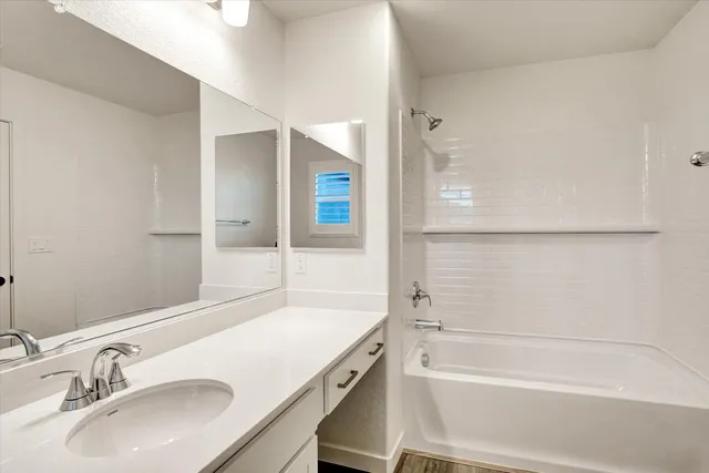 a bathroom with a granite countertop sink mirror and a bathtub