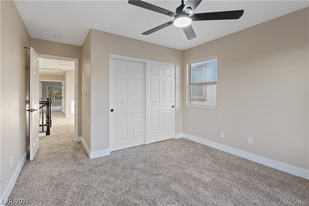 1662 Ravanusa Drive Henderson, NV 89052 - Photo 29 of 74 A well-lit bedroom features plush carpeting and a modern ceiling fan, offering a comfortable personal retreat.