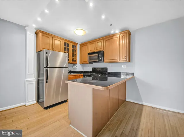 a kitchen with stainless steel appliances granite countertop a refrigerator a stove a sink and a microwave