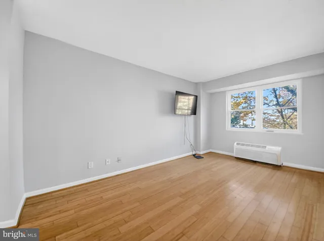 an empty room with wooden floor and window