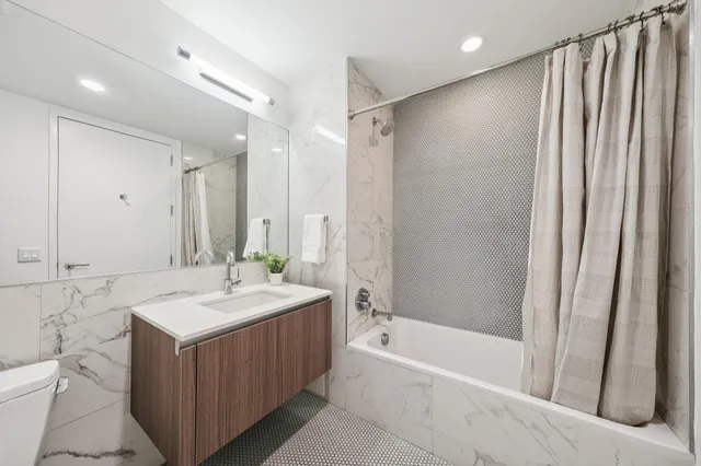 a bathroom with a sink double vanity mirror and a bathtub