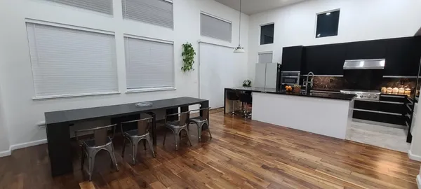 a kitchen with stainless steel appliances granite countertop a stove top oven a sink dishwasher a dining table and chairs with wooden floor