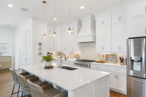 a kitchen with stainless steel appliances granite countertop a white table chairs and a refrigerator