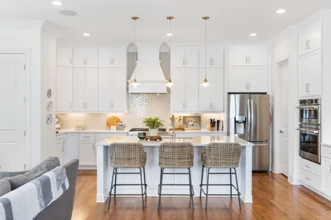 a kitchen with stainless steel appliances granite countertop a kitchen island hardwood floor and chairs
