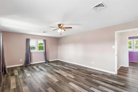 a view of an empty room with window and wooden floor