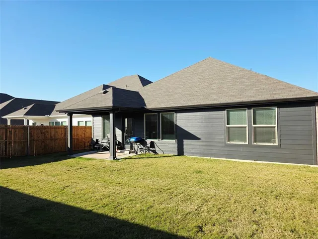 a view of a house with floor to ceiling windows and a yard