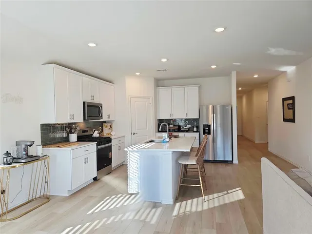 a kitchen with stainless steel appliances kitchen island granite countertop a sink a stove a refrigerator cabinets and a dining table