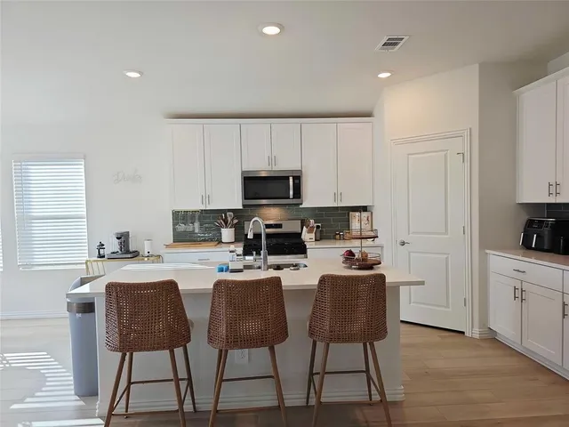 a kitchen with stainless steel appliances granite countertop a stove a sink a microwave a dining table and chairs