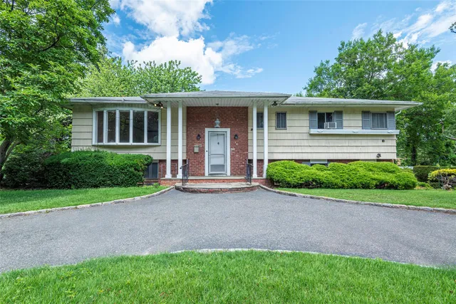 a front view of a house with a yard and potted plants