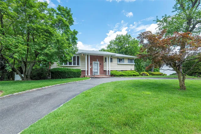 a view of house with a big yard and large trees