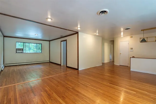 a view of an empty room with window and wooden floor
