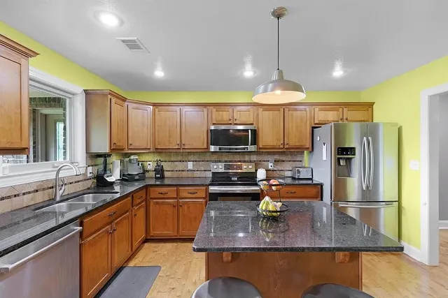 a kitchen with stainless steel appliances granite countertop a sink refrigerator and microwave