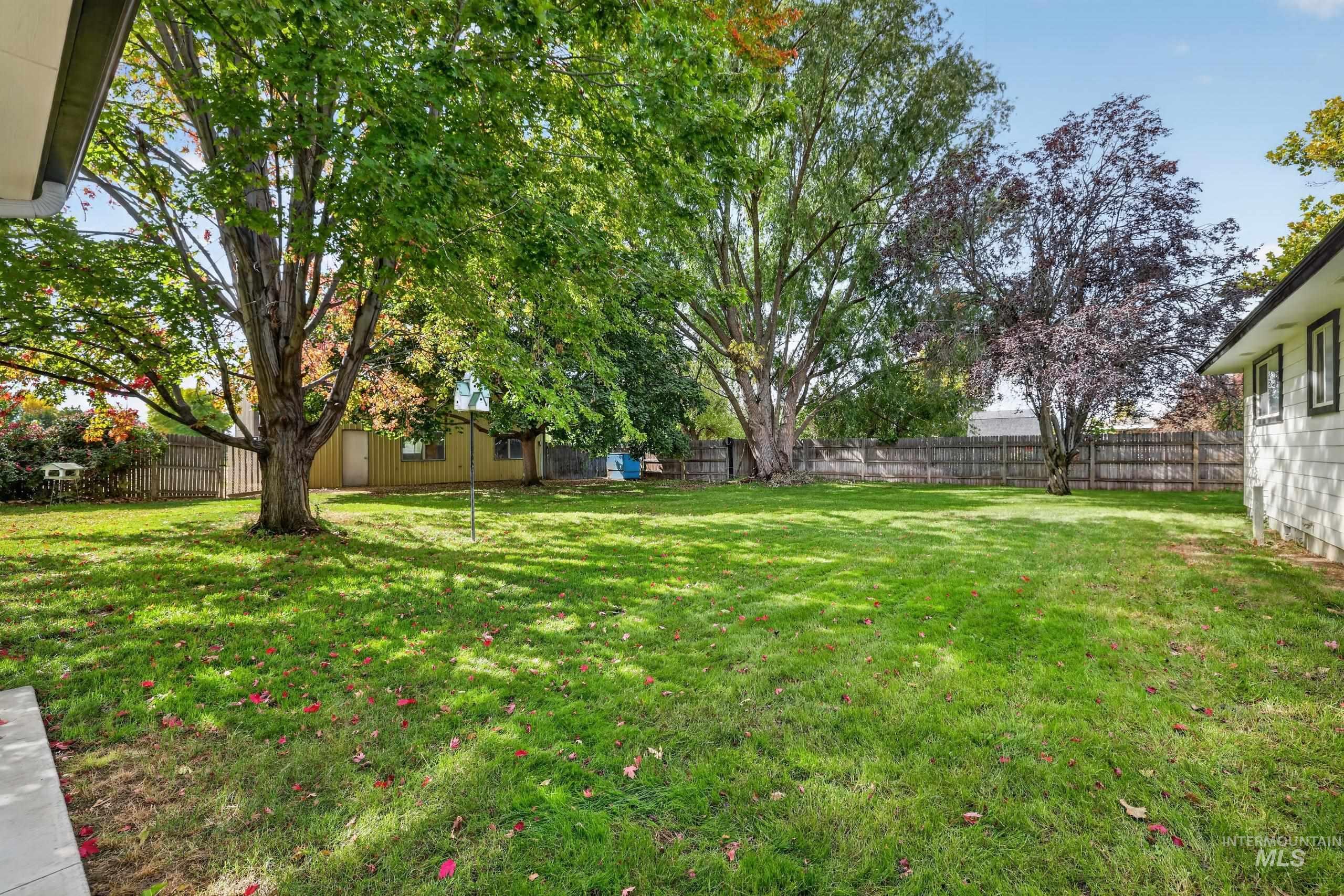 9055 West Highlander Road Boise, ID 83709 - Photo 28 of 39 Expansive backyard featuring a manicured lawn, mature trees, and a privacy fence