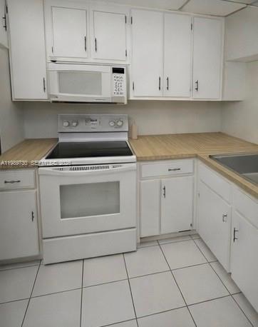3531 Inverrary Drive, Unit 310 Lauderhill, FL 33319 - Photo 5 of 10 a kitchen with granite countertop white cabinets and white appliances