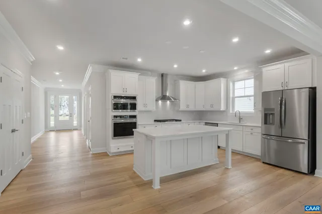 a large kitchen with stainless steel appliances granite countertop a large counter top and wooden floors