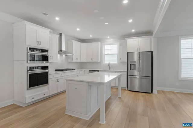 a kitchen with stainless steel appliances granite countertop a refrigerator a stove a sink and white cabinets