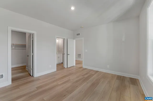 a view of an empty room with wooden floor & closet