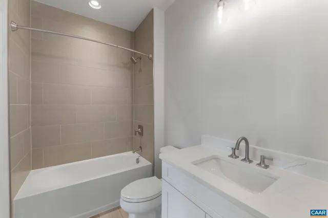 a bathroom with a bathtub shower sink vanity and toilet