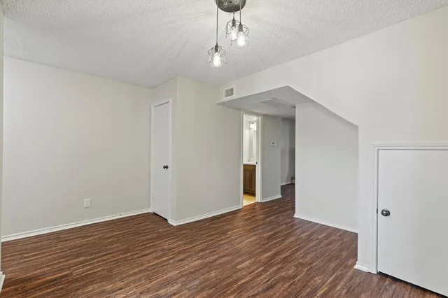 a view of a hallway with wooden floor and chandelier