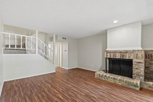 a view of a livingroom with wooden floor and a fireplace
