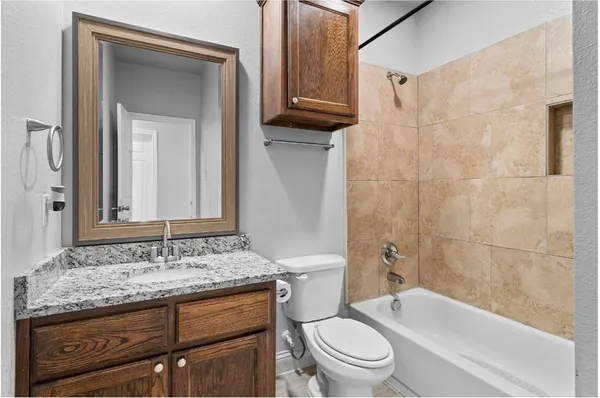 a bathroom with a granite countertop toilet a sink and bathtub