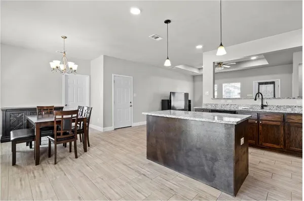 a large kitchen with kitchen island a dining table chairs and a chandelier
