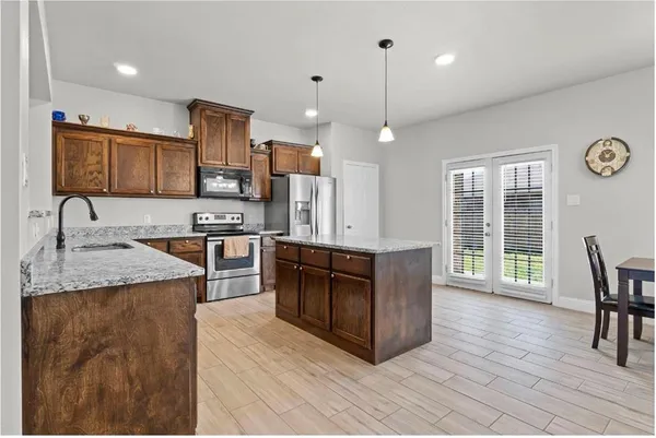 a large kitchen with stainless steel appliances granite countertop a stove a sink dishwasher a microwave oven with cabinets and wooden floor