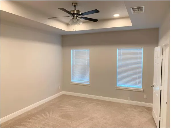 an empty room with windows and fan