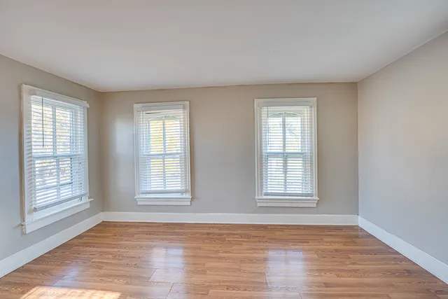 a view of an empty room with wooden floor and window