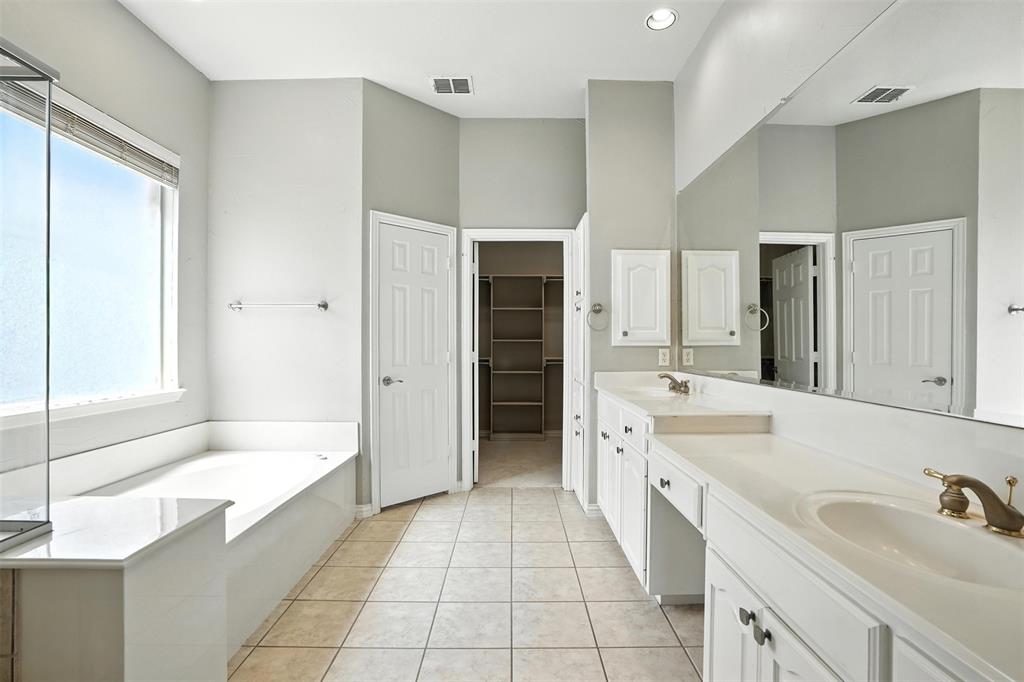 8220 Holliday Road Lantana, TX 76226 - Photo 20 of 40 Spacious bathroom featuring an integrated soaking tub, a large window with privacy treatment, an extended double vanity with integrated sinks, and ample cabinetry