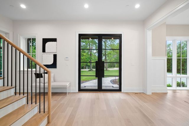 a view of an empty room with wooden floor and stairs