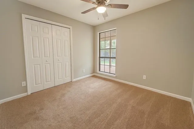 an empty room with windows and chandelier fan