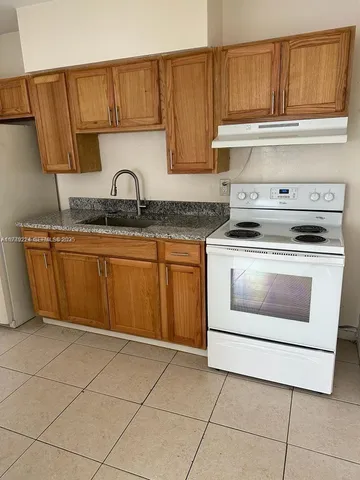 a kitchen with granite countertop a stove top oven microwave and cabinets