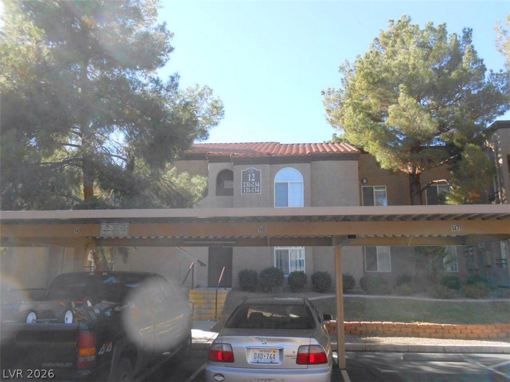9325 West Desert Inn Road, Unit 132 Las Vegas, NV 89117 - Photo 19 of 36 A terracotta tile roof accents this multi-level residential building, shaded by mature trees.