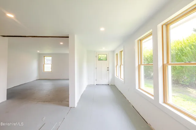 a view of an empty room with window and wooden floor
